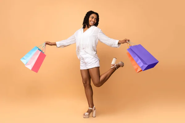 Africano donna su shopping posa con borse su beige sfondo — Foto Stock