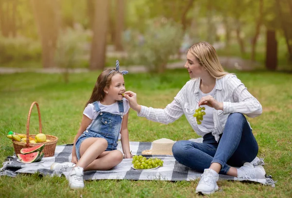 Moderns matande dotter som ger sina druvor att ha familje picknick utanför — Stockfoto