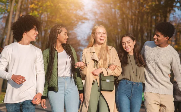 Jóvenes amigos gozosos caminando por el parque público —  Fotos de Stock