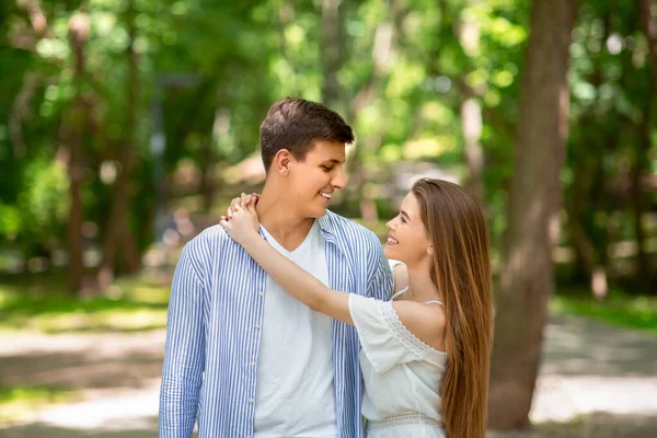 Attraktives Mädchen blickt ihren Freund mit Liebe an und umarmt ihn im Park — Stockfoto