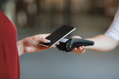 NFC Teknoloji. Tanımlanamayan bir kadın akıllı telefonuyla terminale ulaşılamayan bir ödeme yapıyor.