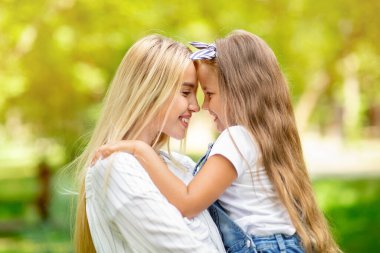 Sevimli anne ve küçük kız dışarıda birbirlerine gülümsüyorlar.