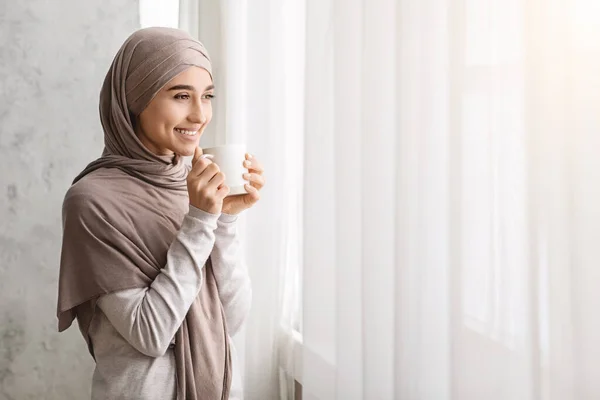 Perempuan Arab relaks Dalam Hijab Menikmati Kopi Pagi Dekat Jendela Di Rumah — Stok Foto