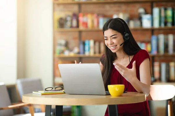 Telekonferans. Gülümseyen Asyalı kadın kafede laptopta video görüşmesi yapıyor. — Stok fotoğraf