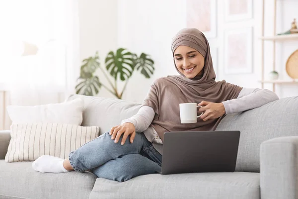 A casa Passtime. Alegre árabe mujer viendo películas en el ordenador portátil y beber café — Foto de Stock