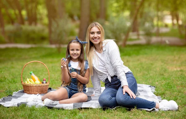 Mor och dotter blåser såpbubblor sitter i parken — Stockfoto