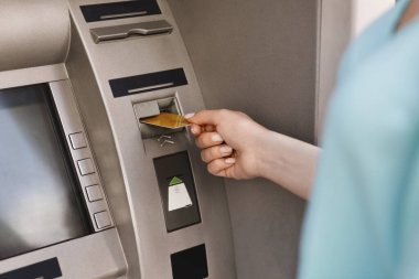 ATM makinesine kredi kartı takan bir kadının elini kapat.