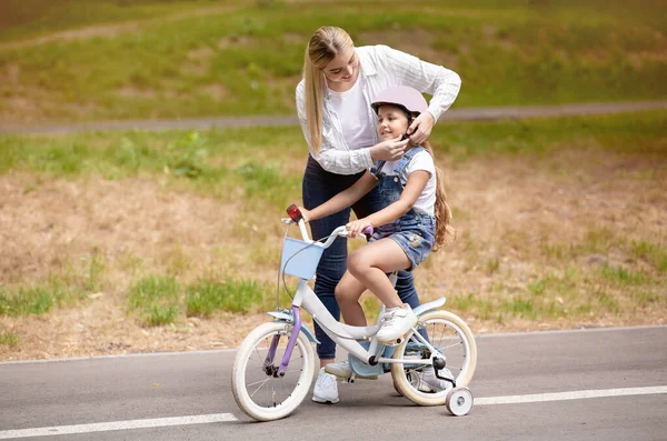 Mère enseignant la fille à monter à vélo avec des stabilisateurs à l'extérieur — Photo