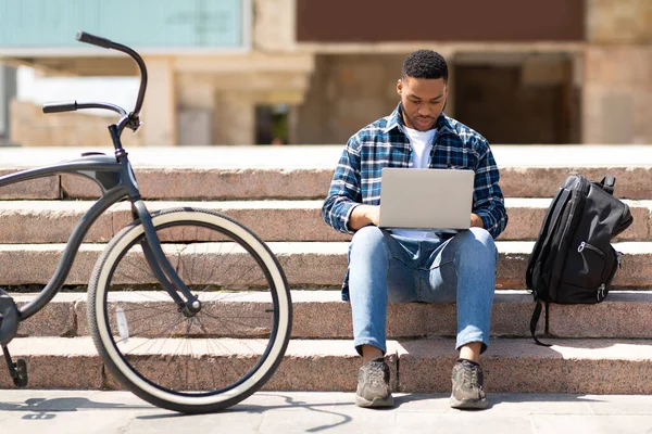 Estudante usando laptop, sentado nos degraus da cidade — Fotografia de Stock