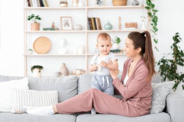 Mutlu genç anne ve onun sevimli küçük çocuğu evde oynuyorlar.