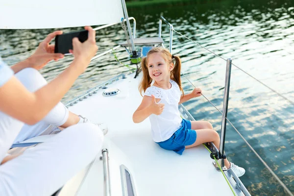 Mãe tirando foto de filha Gesturing Thumbs-Up desfrutando de cruzeiro de iate — Fotografia de Stock