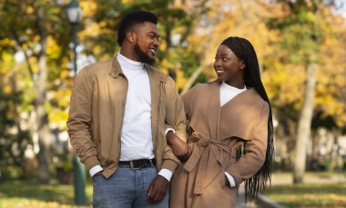 Sonbahar parkında birlikte yürüyen siyah milenyum çifti portresi.