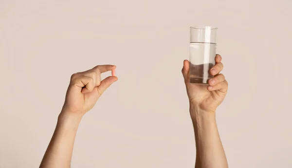 Vista recortada del hombre milenario sosteniendo vaso de agua y píldora sobre fondo claro, primer plano — Foto de Stock