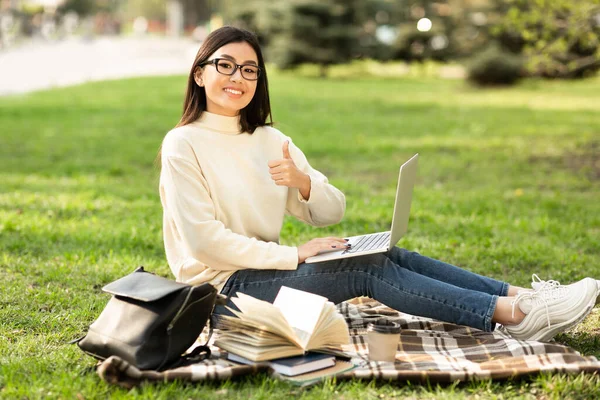 Étudiant utilisant un ordinateur portable, assis dans le parc près du campus — Photo
