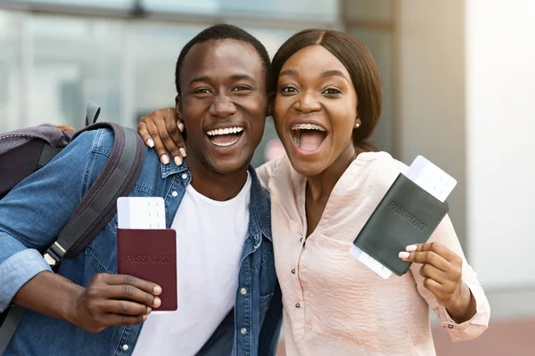 Vacaciones, por fin. Emocional pareja africana alegre sosteniendo pasaportes y entradas — Foto de Stock