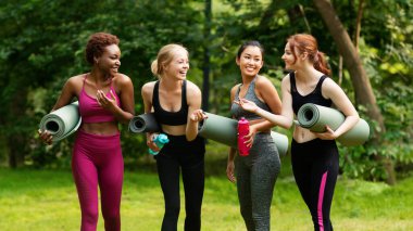 Bir grup milenyum kızı doğadaki yoga pratiklerinden önce iletişim kuruyor.