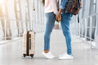 Romantik siyah çift birlikte seyahat ediyor, havalimanında el ele tutuşuyorlar.