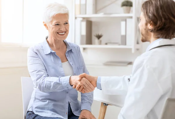 Feliz apretón de manos de mujer mayor con médico personal en el consultorio — Foto de Stock