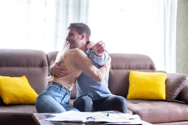 Jongeman met huissleutel en knuffelen zijn vrouw in nieuw huis — Stockfoto