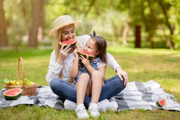 Šťastná matka a dítě dívka jíst meloun těší den venku — Stock fotografie