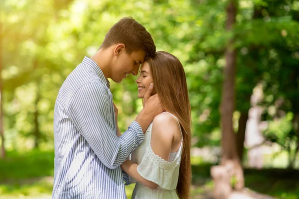 Romantik bir ilişki. Yakışıklı genç adam ve kız arkadaşı yaz günü parkta sarılıyorlar. — Stok fotoğraf