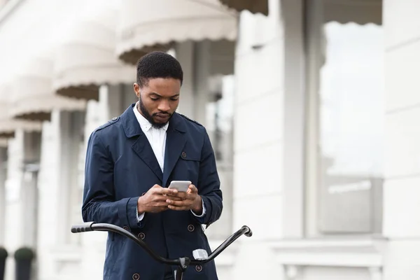 Bonito empresário mensagens de texto no telefone sentado na bicicleta — Fotografia de Stock