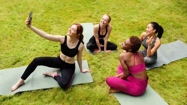 Grupo de belas meninas esportivas tomando selfie antes de sua prática de ioga na natureza — Fotografia de Stock