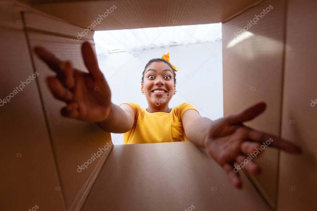 Excited african woman unpacking, opening carton box