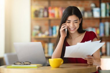 Kumanda Ofisi. Asyalı Kız Kafe 'de gazeteleri kontrol ediyor ve cep telefonuyla konuşuyor.