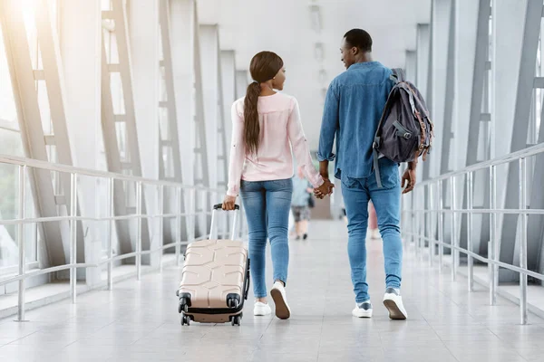 Romantický černošky pár chůze s kufry v terminálu letiště, držení za ruce — Stock fotografie