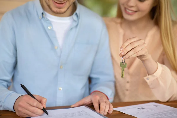 Primer plano de la pareja milenaria con la clave de su nuevo acuerdo de arrendamiento de la firma de la casa — Foto de Stock