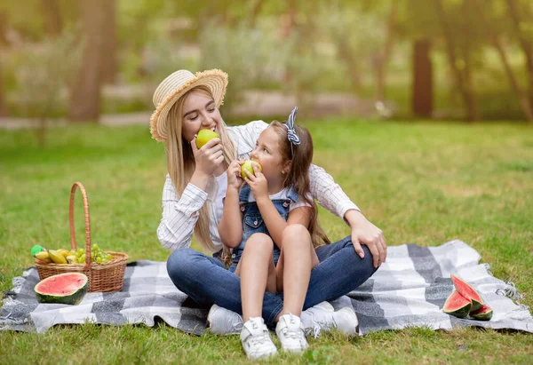 Mor och dotter på picknick äta äpplen sitter i parken — Stockfoto
