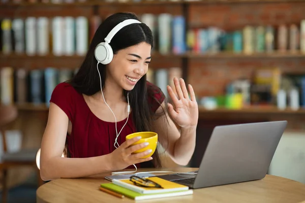 Videollamada. Amistoso asiático chica en auriculares usando portátil en café —  Fotos de Stock