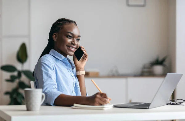 Millennial Black Woman Manager macht sich Notizen und telefoniert im Büro — Stockfoto