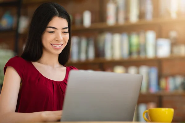 Comunicação online. Sorrindo asiático menina usando laptop na cidade café, respondendo e-mails — Fotografia de Stock