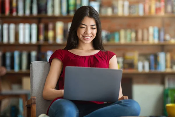 Lächelnd asiatisch student mädchen vorbereitung für prüfung mit laptop bei bibliothek — Stockfoto