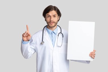 Doktor boş uyarı işareti tutuyor ve parmağıyla işaret ediyor.