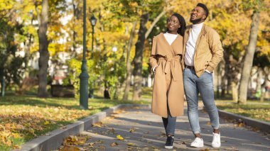 Şehir parkında yürüyen ve doğanın tadını çıkaran güzel, romantik siyah çift.