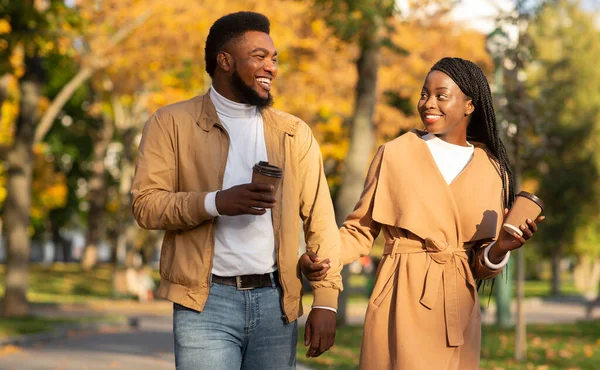 Giovane coppia afro bere un caffè mentre si cammina nel parco autunnale — Foto Stock