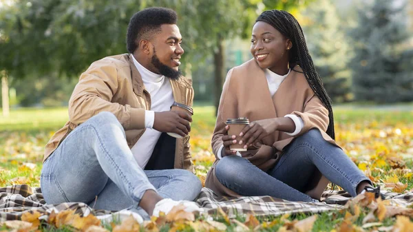 Black couple sitting on picnic in autumn park and drinking coffee — Stock Photo, Image