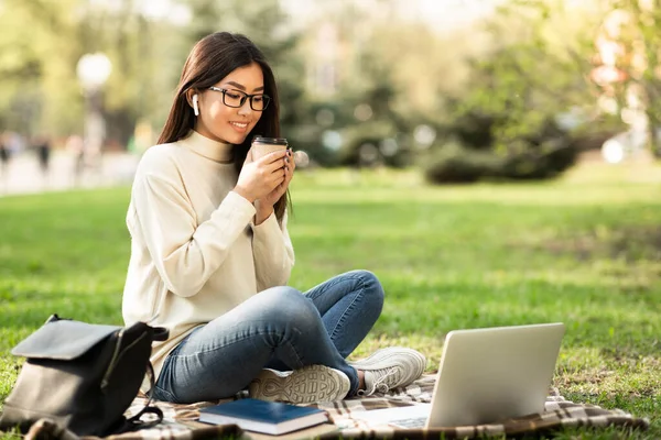 Chica bebiendo café, usando el portátil, sentado en el parque — Foto de Stock