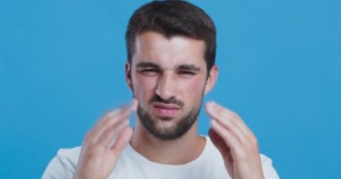 Genç adam yüksek tansiyondan muzdarip, masaj yapıyor ve yüzünü buruşturuyor.