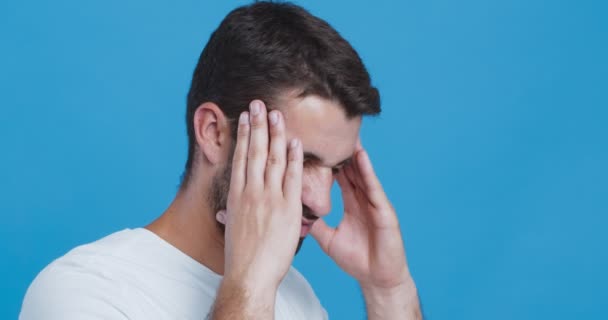 Biały mężczyzna cierpiący na ostry ból głowy, pocierający skronie — Wideo stockowe
