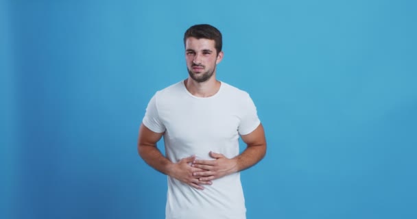 Молодий чоловік з болем в животі, торкається його шлунка — стокове відео