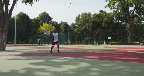 Αφροαμερικάνος που παίζει μπάσκετ, ρίχνει μπάλα στο καλάθι του μπάσκετ. — Αρχείο Βίντεο