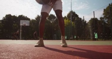 Afrikalı Amerikalı basketbolcu dışarıda top sürüyor.