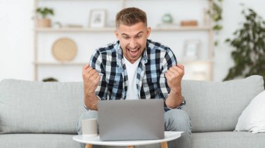 Heyecanlı yakışıklı adam bilgisayarını kullanarak kendinden geçiyor.