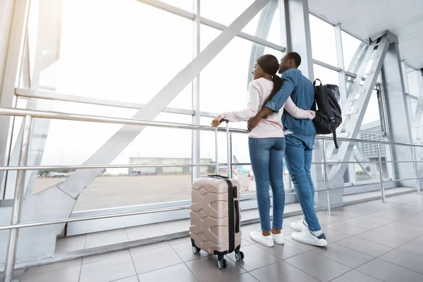 Romantic african american couple standing near window at airport and hugging — Stock Photo, Image