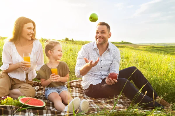 Счастливый папа жонглирует яблоками на пикнике снаружи — стоковое фото