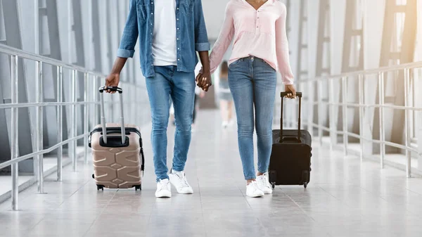 Viajando juntos. Pareja negra caminando con maletas en la terminal del aeropuerto, sosteniendo las manos — Foto de Stock